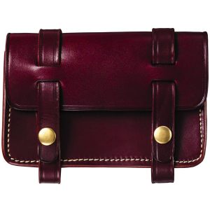 The Josiah Rifle Cartridge Box is a burgundy leather satchel featuring a flap closure, secured by two buckled straps and adorned with bronze-tone buttons.